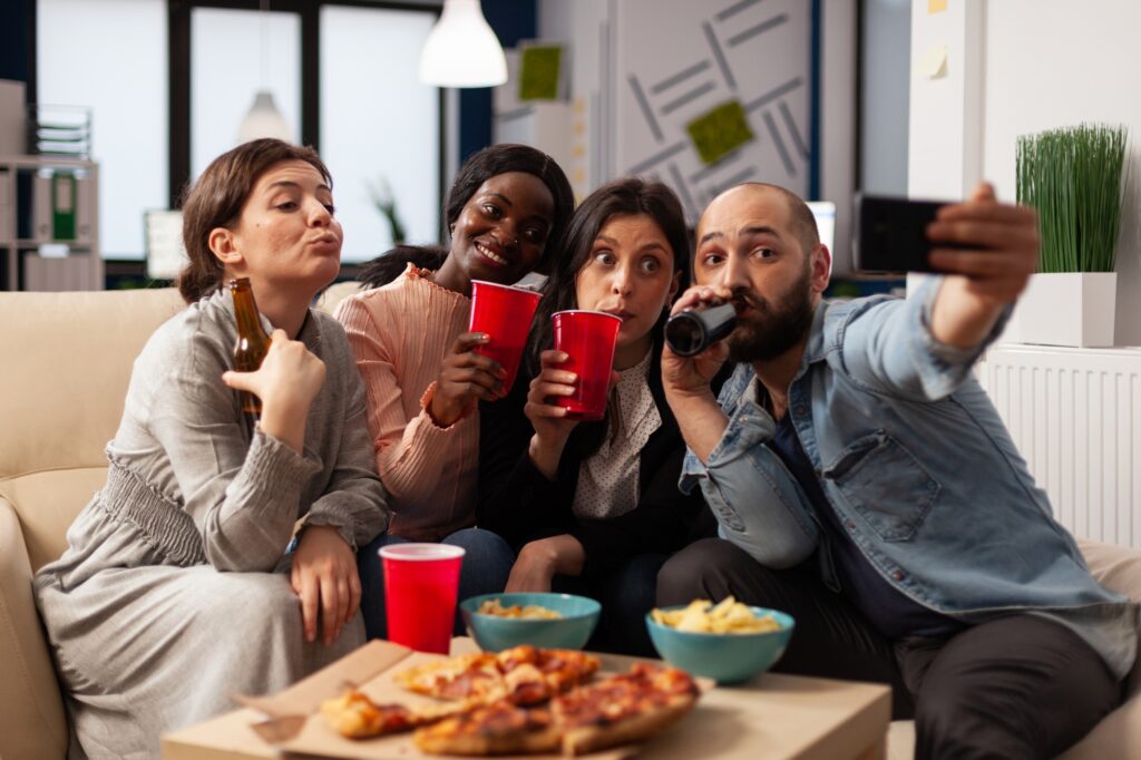 Group of people taking selfies and celebrating with drinks