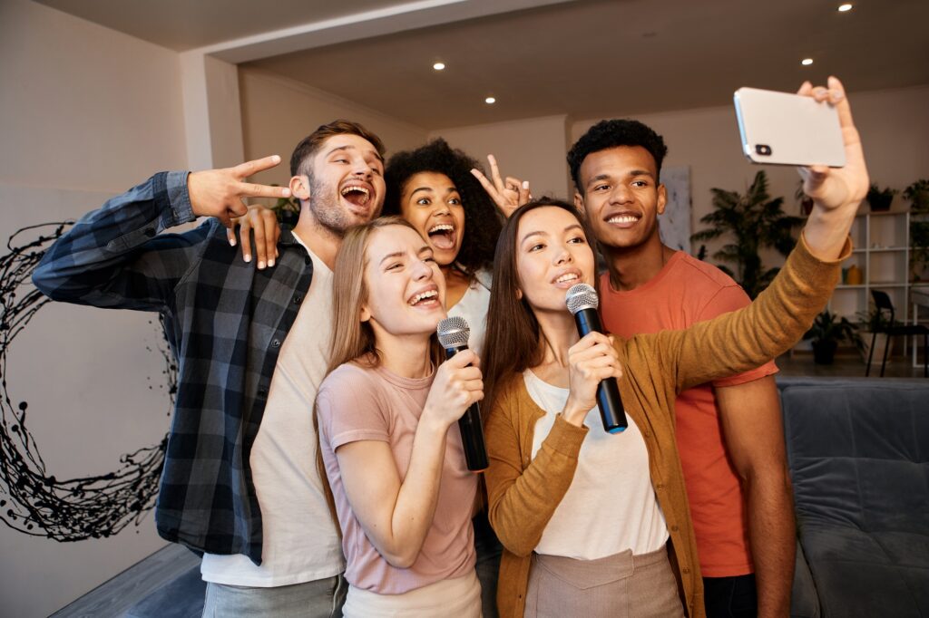 Selfie time. Group of young happy multicultural friends taking a selfie using smartphone while